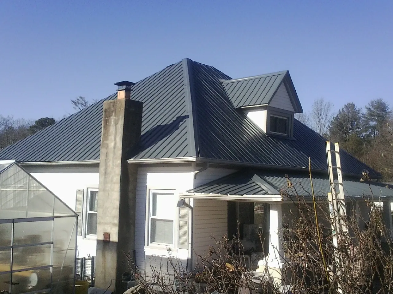 Dark blue standing seam metal roof on a white farmhouse with dormer — Slate & Tile Roof Repair by Roofing Brothers in Peacham