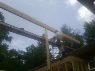 Carpenter setting a ridge beam over a new addition frame — Ice Dam Removal by Roofing Brothers in Peacham
