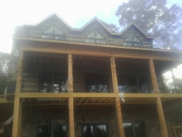 Dormers and porch framing on a large log home under construction — Roof Coating work by our crew in Peacham