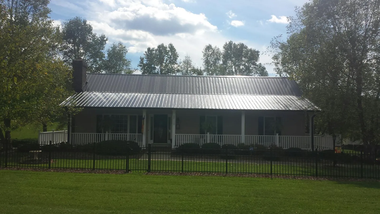 Gray metal roof on a brick ranch with a full width front porch — Gutter Guard Installation work by our crew in Peacham