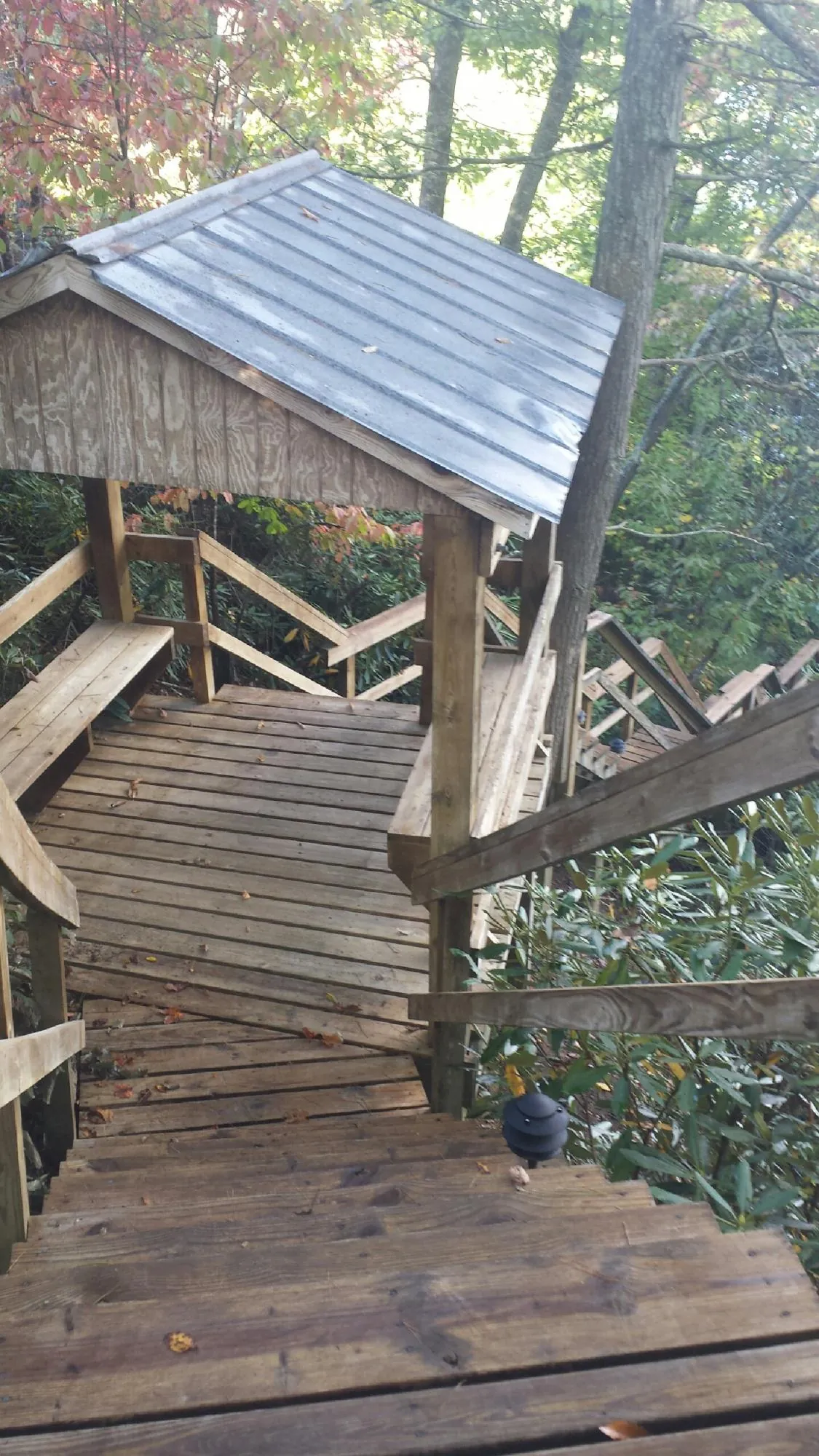 Metal roofed shelter over wooden steps on a wooded walkway — Skylight Repair & Installation work by our crew in Peacham
