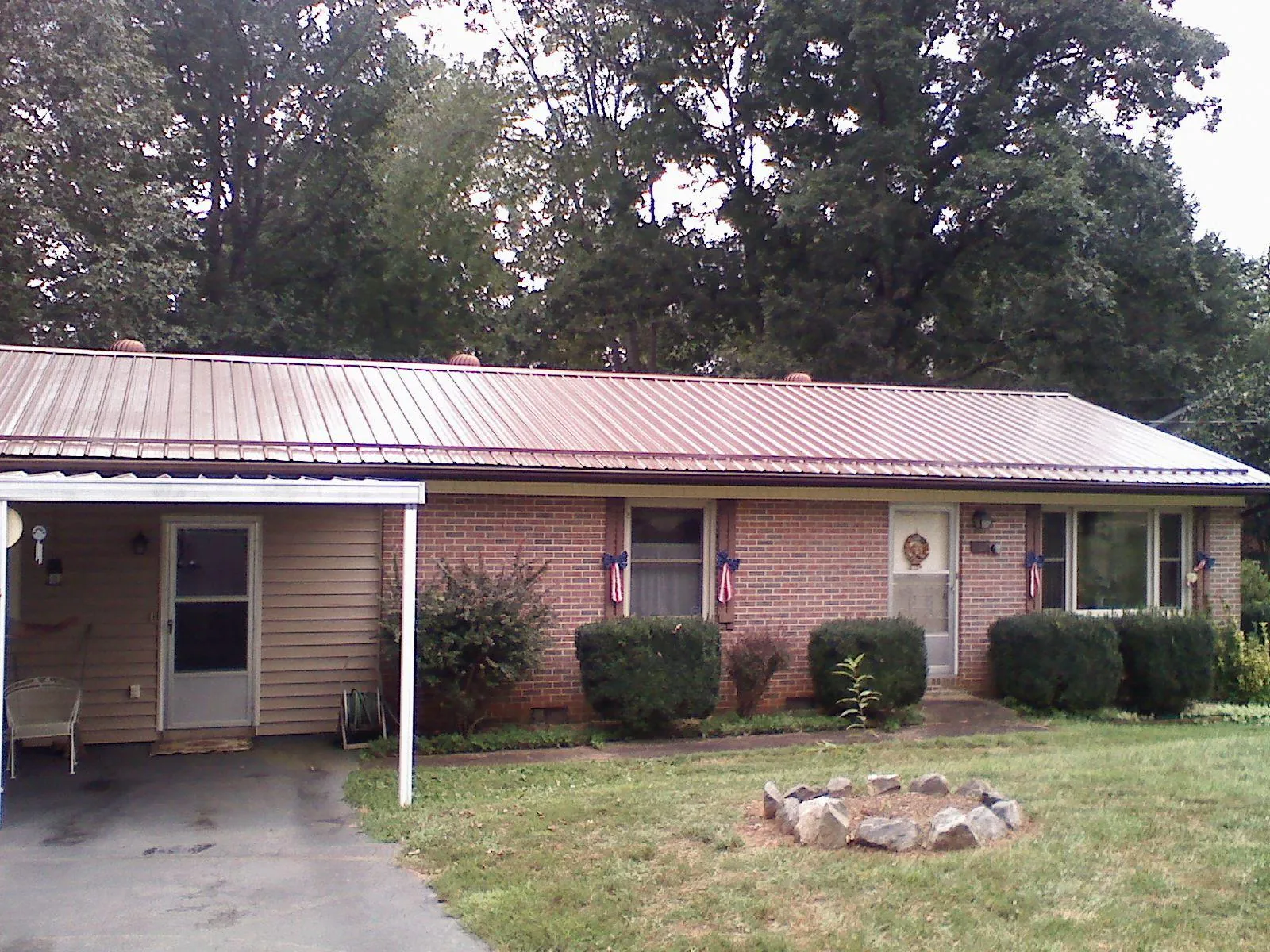 Bronze metal roof and carport on a brick ranch home — Roof Repair work by our crew in Peacham