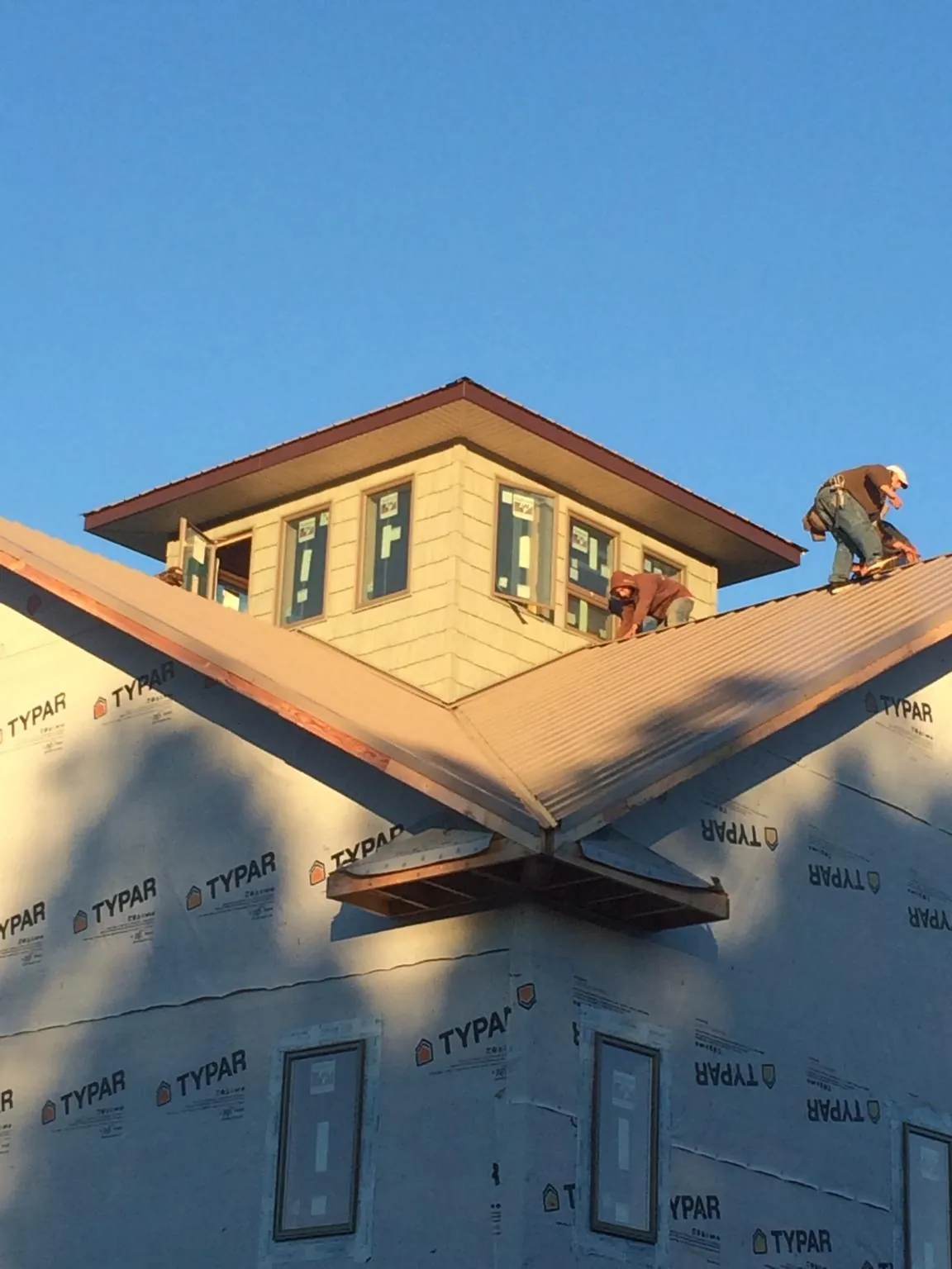 Roofers working around a rooftop cupola on a new metal roof at sunset — Roof Waterproofing in Peacham by Roofing Brothers